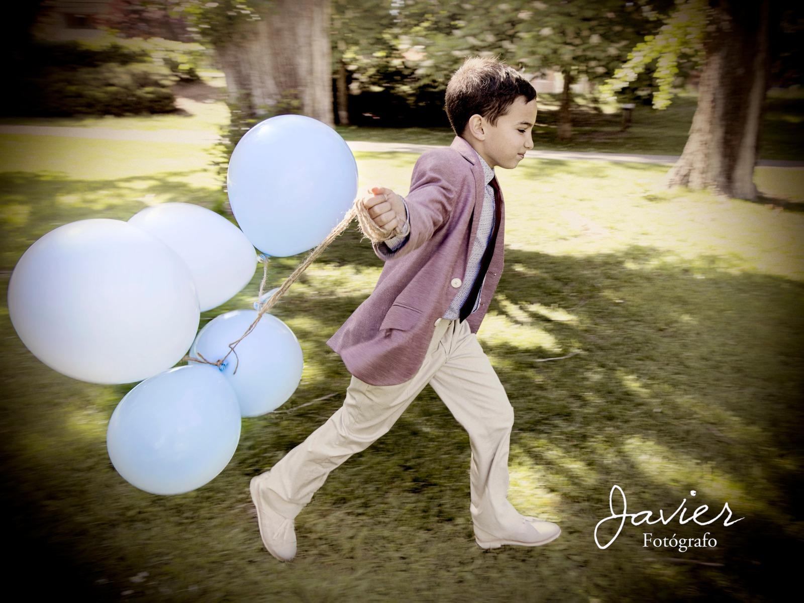 Niño de Comunión caminando con globos en un parque en Valladolid