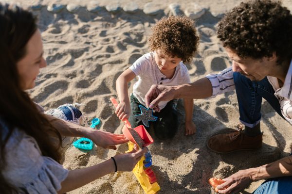 Familia jugando junta en la arena durante unas vacaciones en la playa